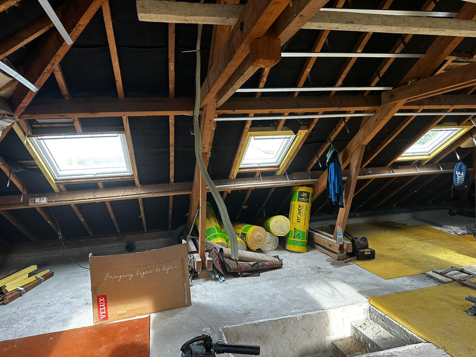 Combles en cours de rénovation, rouleaux d'isolant au pied de la charpente